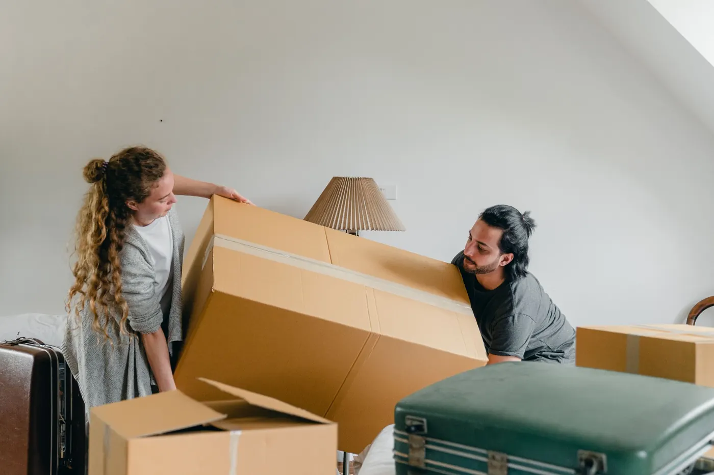 Two people lifting a large cardboard box together