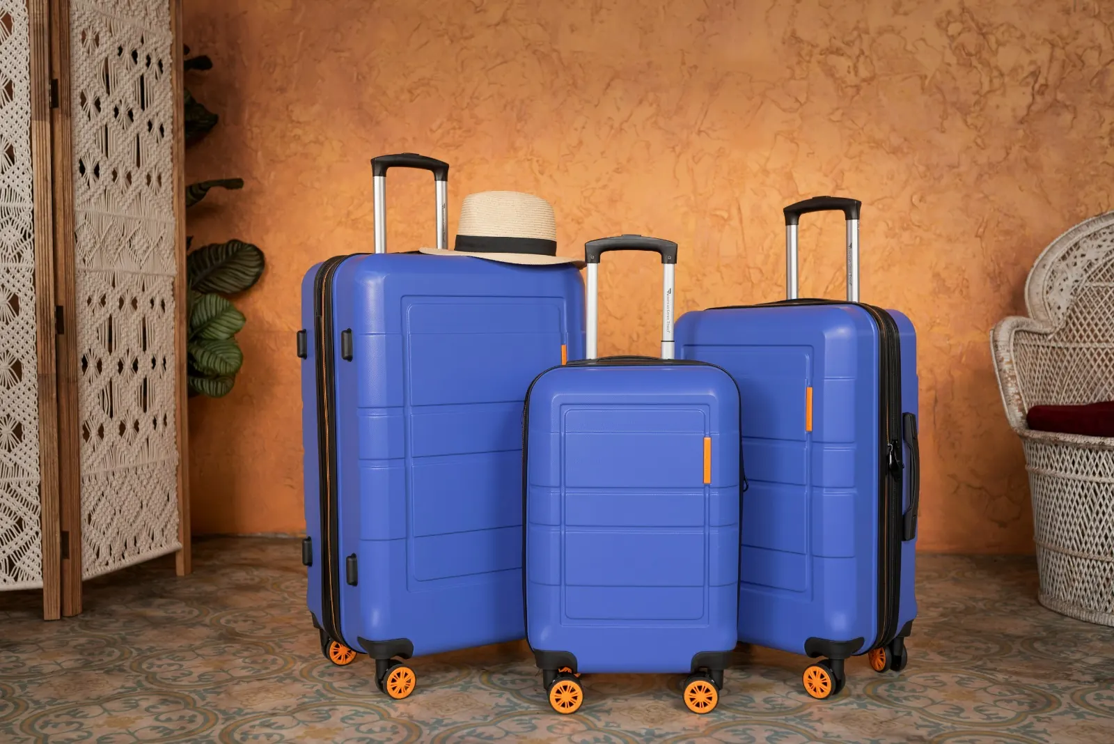 Three blue suitcases with orange wheels and a straw hat