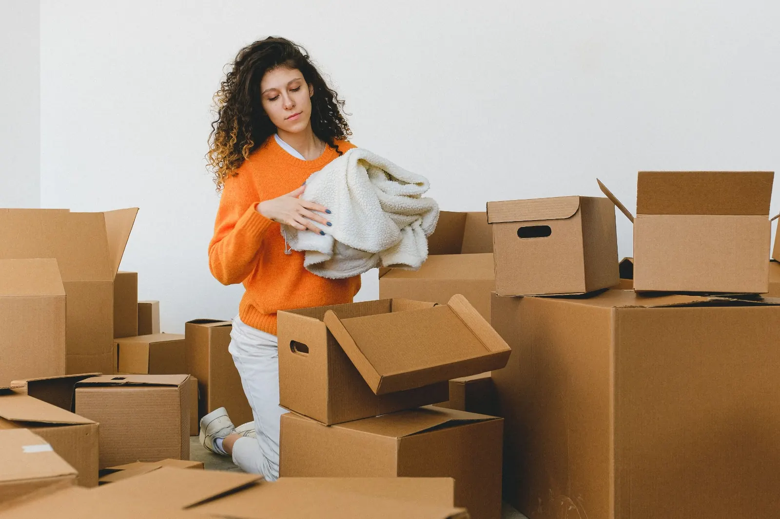 A woman packing a soft blanket into cardboard boxes